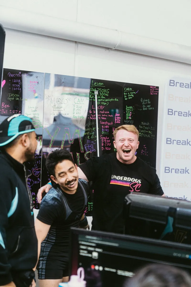 An Underdogs SC coach laughing with a lifter between attempts at a powerlifting meet